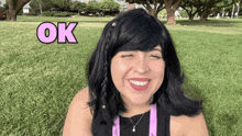 a woman in a black wig is smiling with the word ok above her