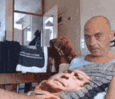 a bald man is sitting on a couch with a picture of a man on his chest