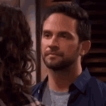 a man with a beard is looking at a woman in a room .