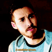 a man with a beard says " a reminder of you " in yellow letters