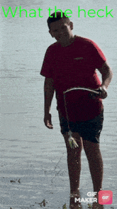 a boy in a red shirt is standing in the water holding a fishing rod with the words what the heck written above him