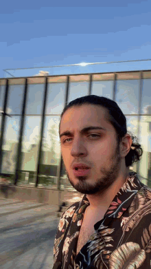 a man with long hair and a beard wearing a floral shirt
