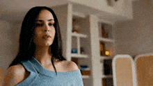 a woman in a blue sweater is standing in a living room