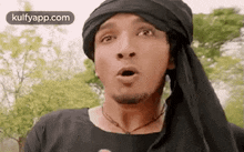 a man with a turban on his head is making a funny face .