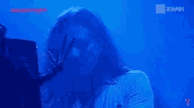 a man with long curly hair is playing a guitar in front of a blue background with the word zwei on it