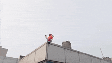 a man is standing on the roof of a building holding a bucket