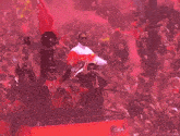 a man is holding a trophy in front of a crowd with a flag that says ' liverpool ' on it