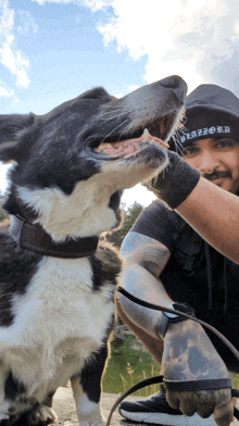 a man petting a black and white dog wearing a hat that says razor on it
