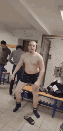 a shirtless man is dancing in a locker room with other men