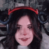 a close up of a woman wearing headphones and a red headband with horns on her head .