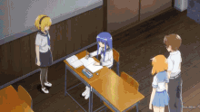 a group of anime characters stand around a desk