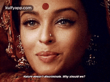 a close up of a woman 's face with a red dot on her forehead and earrings .