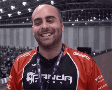 a man wearing a red and black panda global shirt smiles