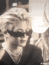 a close up of a person wearing sunglasses and a pearl necklace