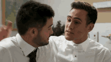 two men in white shirts and bow ties are looking at each other with a sign in the background that says discovery