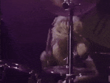 a man without a shirt is playing drums in a dark room .