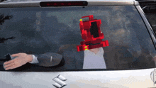 a suzuki car has a sticker on the back window that shows a man with a red robot on his head
