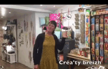 a woman in a yellow dress is standing in a room with a sign that says crea 'ty breizh on it