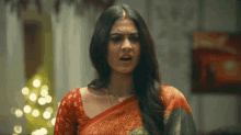 a woman in a red and green sari is making a funny face .