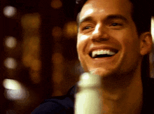 a close up of a man 's face with a bottle in the background