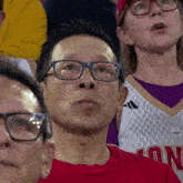 a man wearing glasses sits in a crowd wearing a jersey that says ' nc ' on it