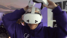 a man in a purple hoodie is wearing an oculus rift virtual reality headset .