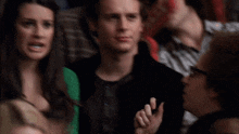 a man and a woman are sitting in a crowd and the man is wearing a sign that says ' maxed '
