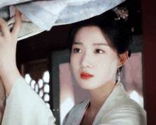 a woman in a white dress with a flower in her hair looks down
