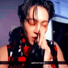 a close up of a man covering his face with his hands .