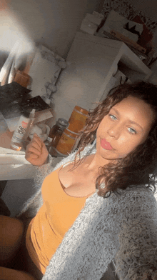 a woman in a yellow tank top is taking a selfie with a spray bottle that says go go
