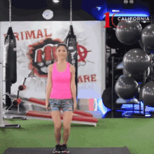 a woman in a pink tank top and shorts is standing on a yoga mat in front of a sign that says rimal
