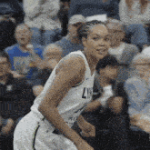 a woman in a lynx jersey stands on a court