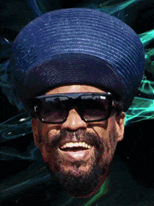 a man wearing a blue hat and sunglasses smiles