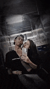 a man and a woman are taking a selfie in an elevator and the man is wearing a shirt that says marty