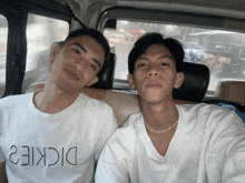 a man wearing a dickies t-shirt sits next to another man in a car