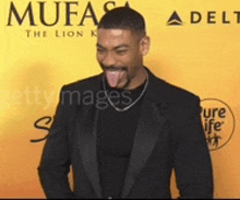 a man in a suit is sticking his tongue out in front of a delta sign