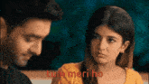 a man and a woman are sitting next to each other and the woman is looking at the man with a sad look on her face .