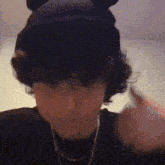 a young man wearing a mickey mouse hat and a necklace is making a funny face .