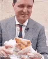 a man in a suit and tie is eating a sandwich .