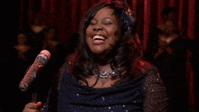 a woman singing into a microphone in front of a choir