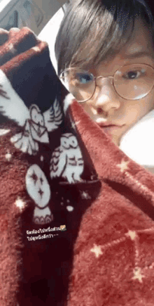 a person wearing glasses is wrapped in a blanket