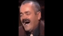 a man with a missing tooth is laughing with his mouth open and his eyes closed .