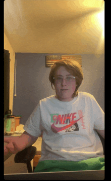 a person wearing a white nike shirt is sitting in front of a computer