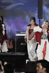 a group of people are dancing on a stage in front of a marshall amplifier