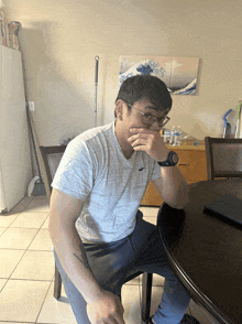 a man in a hollister shirt sits at a table with his hand over his mouth