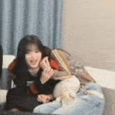 a woman is sitting on a couch holding a teddy bear .