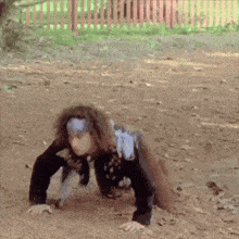 a person is crawling on the ground with a red fence in the background