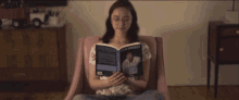 a woman sits in a chair reading a book called the adventures of a girl
