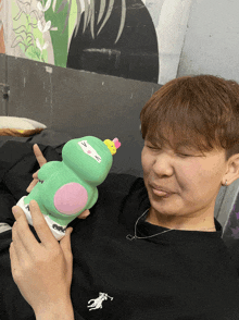 a person wearing a black polo shirt is holding a green toy