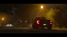 a black car is driving down a street at night